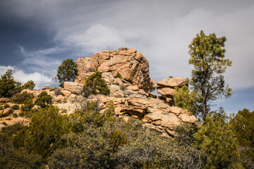 Landscape view of red rock tower lined with pine trees in Hualapai mountains near Kingman Arizona