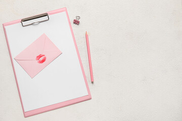 Envelope with lipstick kiss mark and clipboard on white background