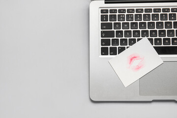 Laptop with lipstick kiss mark on grey background, closeup