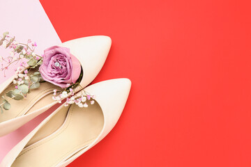 Heels with engagement ring and flowers on color background