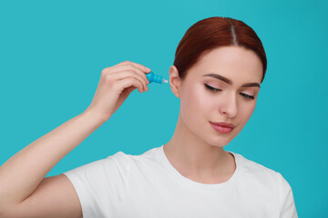Obraz premium Woman using ear drops on light blue background