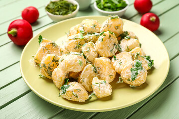 Plate of tasty Potato Salad with dill and parsley on green wooden background