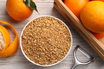 Bowl with dried orange seasoning zest and fruits on white wooden table, flat lay