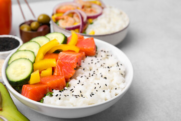 Poke bowls and ingredients on white table, closeup
