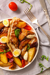Plate of tasty potato salad with eggs, tomatoes and bacon on light background, top view