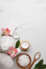 Fototapeta na wymiar Flat lay composition with spa products and flowers on white marble table. Space for text