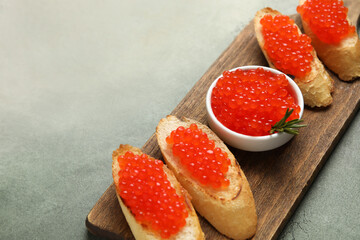 Tasty bruschettas with red caviar on color background
