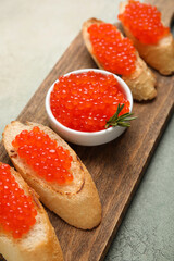 Tasty bruschettas with red caviar on color background