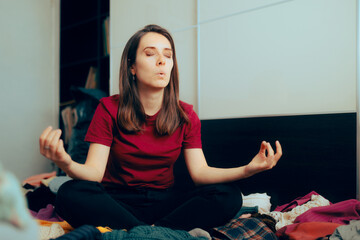 Calm Woman Sitting in Yoga Pose on a Pile of Clothes. Professional organizer taking a deep breath...