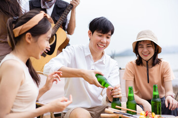 Group of Asian young adult people enjoy drinking a beer together during camping at the park.