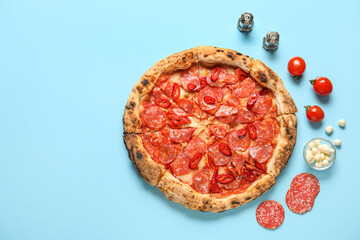 Delicious pepperoni pizza and ingredients on blue background