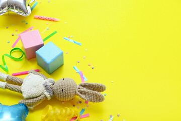 Baby toys with confetti on yellow background, closeup. Children's Day celebration