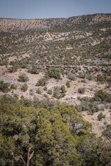 Far view of dirt trail cutting across desert mesas covered in pine bushes and sage brush in spring in western Colorado near town of Montrose