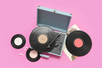 Record player with vinyl disks on pink background