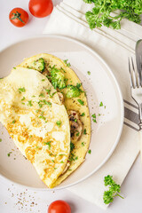 Tasty omelet with broccoli and mushrooms on light table