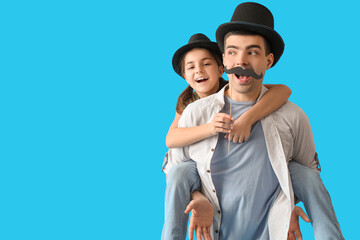 Portrait of father and his little daughter with paper mustache on light blue background