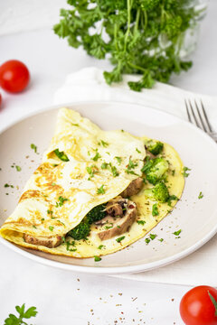Tasty omelet with broccoli and mushrooms on light table