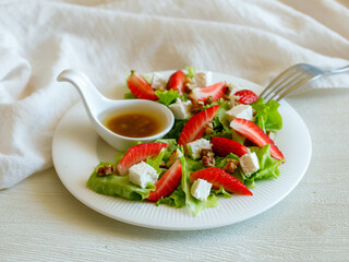 Plate of homemade fresh summer sliced Strawberry and lettuce salad with feta cheese and walnuts. Organic healthy diet, vegetarian salad food
