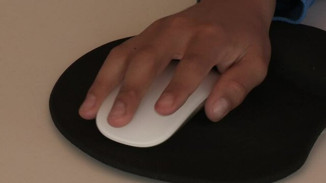 child's hand with white computer mouse and black mat