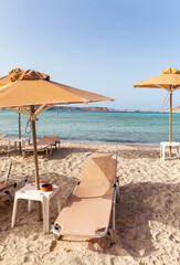 Greece. Crete. Bay of Balos or Lagoon of the Three Seas. View of a cozy sandy beach with umbrellas and sun loungers. The concept of summer holidays at sea