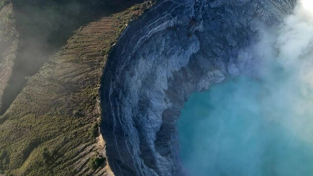 Drone footage of hiking trail on the edge of a volcanic crater with a toxic sulphuric lake inside the crater