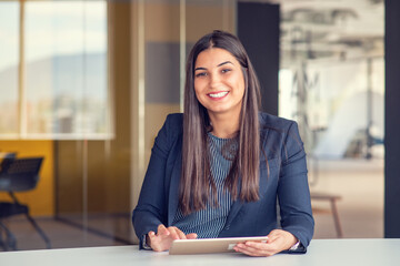 Young attractive female manager working on digital tablet while standing in modern office