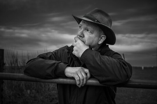 A man in a western style hat pauses to reflect on his thoughts or expresses curiosity.