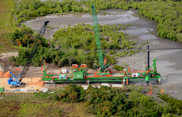 Papua New Guinea-constructing a road across swamp lands using special machinery to cantilever into the muddy environment.