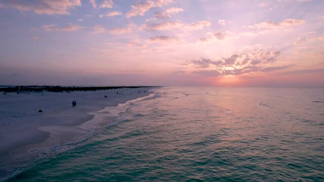 Drone aerial view of sunrise over the Gulf of Mexico's white sand beach and emerald waters  with clouds in the sly