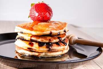 A stack of pancakes with fresh strawberry, honey on top a white wooden background. A healthy breakfast. Copy space