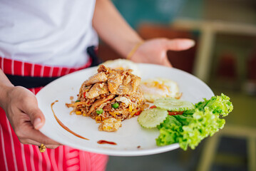 A cook is presenting a Thai fried Rice dish