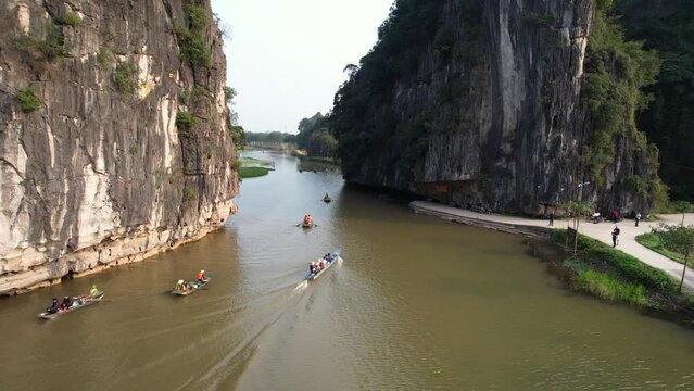 Ninh Binh aerial - Groups of tourists travel on sampan boats on Ngo Dong River in Limestone Gorge at sunset