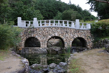 Fototapeta na wymiar a small lake and a white wall stone bridge