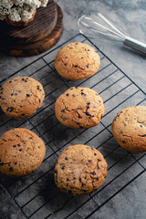 Homemade chocolate chip cookies on black baking cooling tray and abstract background