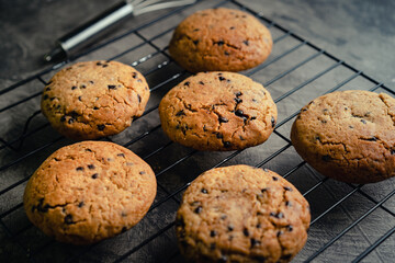 Homemade chocolate chip cookies on black baking cooling tray and abstract background