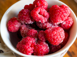 fresh bright frozen raspberries in a cup on the table