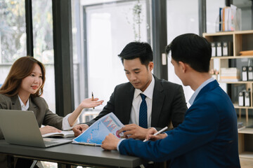 Group of young Asian business people discussing business plan at modern startup in creative business discussing work modern office .