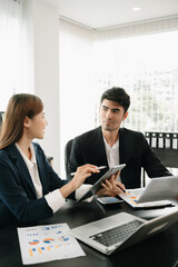 Two business workers talking on the smartphone and using laptop at the office.