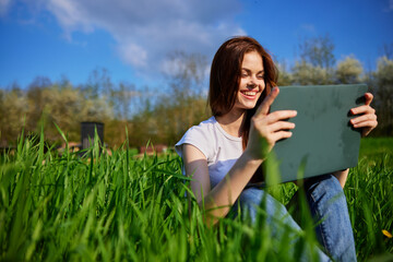 happy woman working on a laptop while on vacation in a high grass field