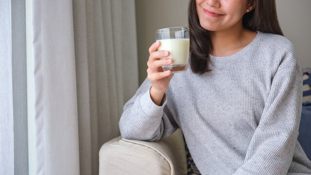 Closeup image of a young woman holding and drinking fresh milk
