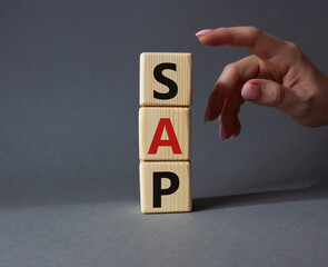 SAP - Systems Applications Products. Wooden cubes with word SAP . Businessman hand. Beautiful grey background. Business and System Application Product concept. Copy space. - obrazy, fototapety, plakaty