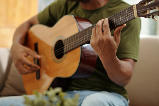 Cropped image of musiccian playing guitar at home