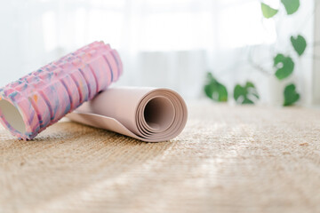 A pink foam massage roller and yoga mat at floor in living room. Foam rolling is a self myofascial release technique. Gym fitness equipment.