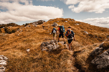 traveler hiking group with backpacks. Hiking in mountains. Sunny landscape. Tourist traveler. Velka...