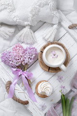 A cup of warm aromatic coffee on a tray and hyacinth flowers