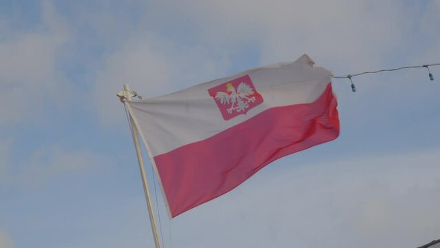 Polish flag with an eagle waving in the breeze against cloudy sky 