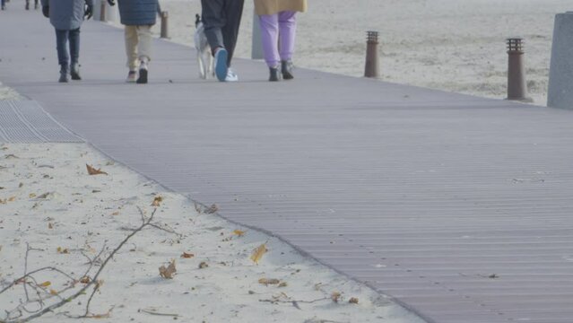 Legs Of People Walking Through The Promenade On A Windy Day. Close Up