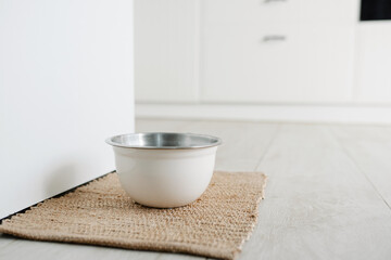 White metalic bowl with dog food or water on the floot in the kitchen home