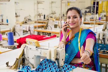 Indian woman talking on smartphone while working at textile factory.