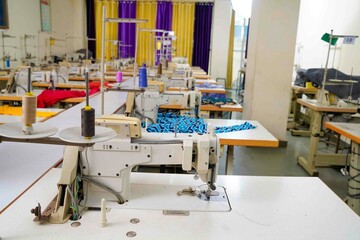 Interior of garment factory making atelier with several sewing machines. Tailoring industry.